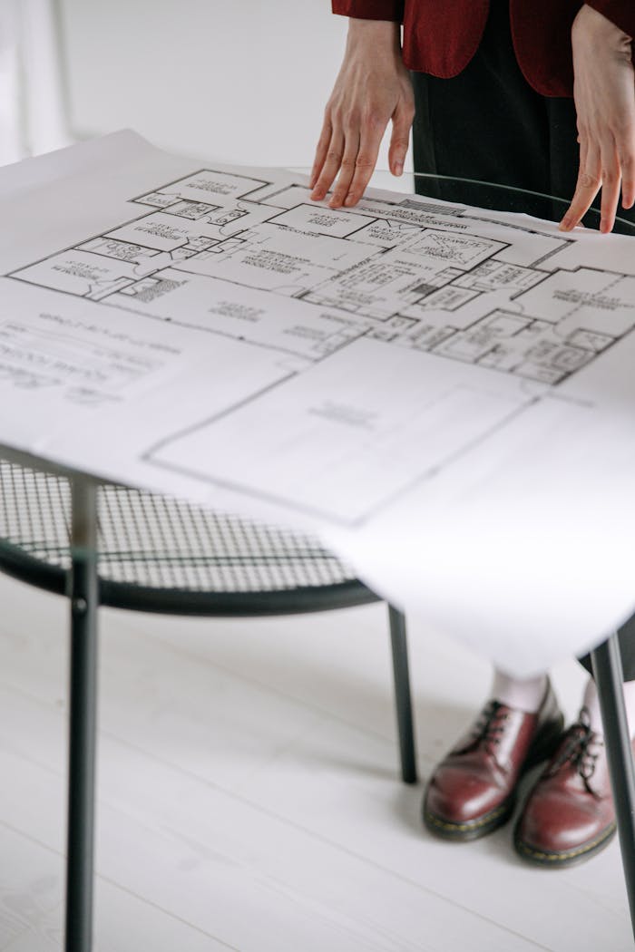 Crafting Captivating Headlines: Your awesome post title goes here Person examining a detailed architectural floor plan on a table indoors with a focus on design.
